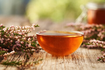 Herbal syrup in a glass bowl with wild heather flowers collected in the forest in autumn