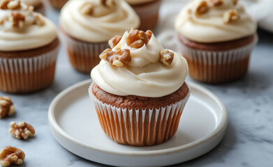 Cupcakes topped with creamy frosting and walnuts on a white plate.