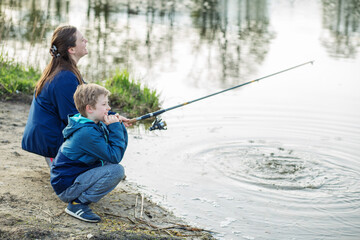 Mother and child patiently fishing by lake. Family time.