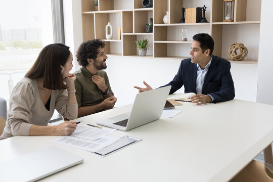 Young man of Indian ethnicity experienced legal advisor consult clients in modern office discuss contract business documents. Successful businessman negotiate startup project with interested investors