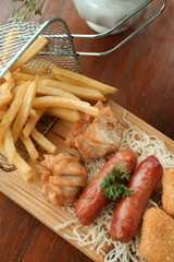 French fries, sausages and nuggets on a wooden chopping board. cafe snack photo concept