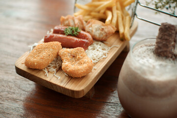 French fries, sausages and nuggets on a wooden chopping board. cafe snack photo concept