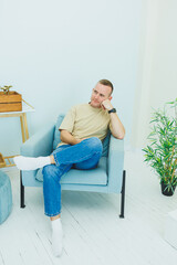 A handsome man sits in a chair and works on the phone. A man is talking on the phone while sitting at home.