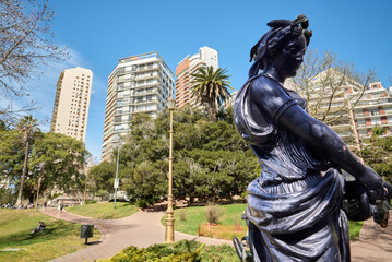 Ancient greek statue of woman with amphora, in a big park with mounds and colonial red tiles