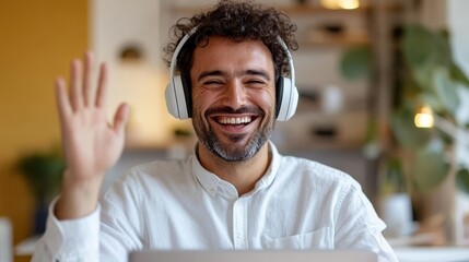 Obraz premium A bearded man in headphones waves enthusiastically during an online meeting, a lively depiction of digital communication and expressive interaction in today’s world.