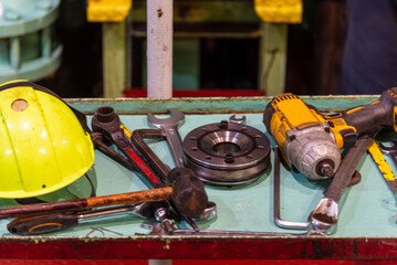 A close-up of various tools scattered across a work platform in the ship's engine room, each...