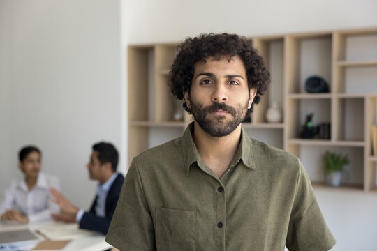 Headshot portrait of inspired young Arabian man starting successful career as intern trainee at international company department. Motivated business staff member looking at camera at workday in office