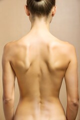 Naklejka premium A back view of a person with a smooth skin tone highlighted against a plain background during a serene indoor setting. Generative AI