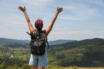 Fototapeta premium Tourist with backpack enjoying picturesque landscape with wide open arms, back view. Space for text
