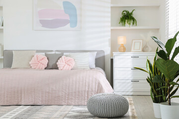 Naklejka premium Large bed, houseplants and decorative elements in room. Stylish bedroom interior