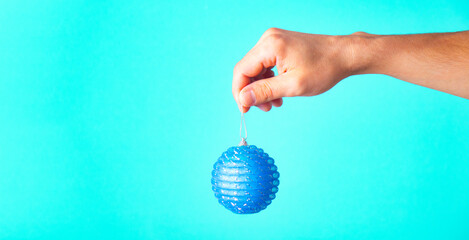 In the hand of a New Year's ball on a blue background with a place for text