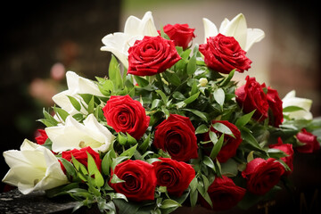 Flower arrangement. Red and white funeral flowers on a gravestone in a cemetery. Relatives have brought memorial flowers to the grave. Beautiful remembrance bouquet.