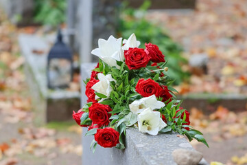 Flower arrangement. Beautiful red and white grave flowers in the cemetery. Relatives want to remember the deceased with flowers. A beautiful bouquet comforts grieving relatives.