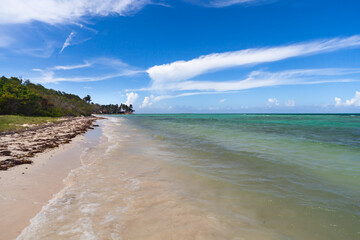 Caribbean sea waterfront, coastline sandy beach; warm turquoise water, hot summer Caribbean day