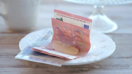 Female hand placing euro banknotes on white saucer. Restaurant bill payment or tipping concept, Financial transaction in dining setting, service industry