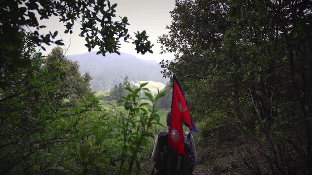 A Man waking in the Jungle of Khaptad National Park with flag of Nepal, travelling in Farwest Nepal