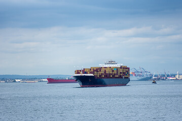 Large, fully loaded container ship sailing under the Verrazano-Narrows bridge on her way out of New...