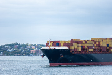 Large, fully loaded container ship sailing under the Verrazano-Narrows bridge on her way out of New...