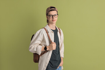 Portrait of teenage boy with backpack on green background