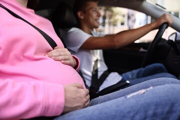 Pregnant woman travelling with her husband by car, closeup