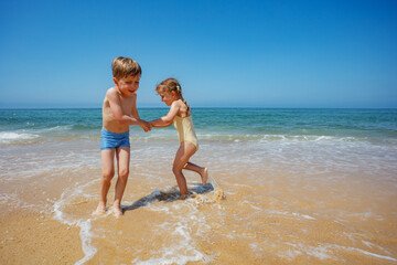 Naklejka premium Children enjoy sunny day by the seaside dancing turning around