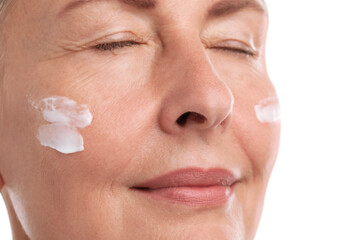 Senior woman with face cream on white background, closeup