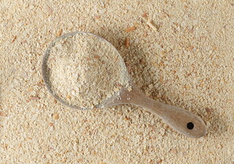 Nutritional yeast pile in wooden spoon (deactivated yeast) background, top view