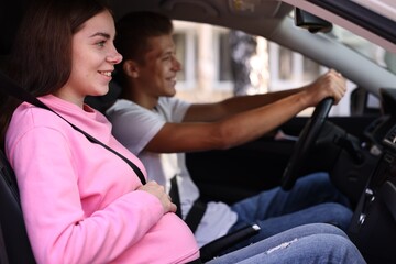 Smiling pregnant woman travelling with her husband by car