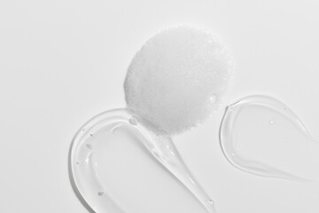 Sample beauty products for facial skin care on white background. Cleanser foam and gel moisturizing cream smear