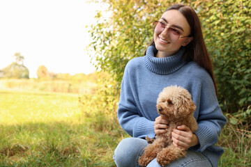 Smiling woman with cute dog outdoors. Space for text