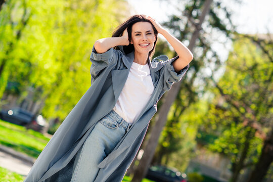 Portrait photo of beautiful young smiling latin attractive lady wearing gray coat walking outdoors relaxed posing stylish outfit in nature