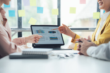 Business Meeting Analysis: A close-up image of a team of professionals gathered around a laptop,...