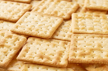 Square water crackers  placed throughout the screen selective focus. Food background.