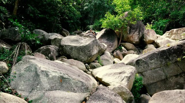 A tourist walks down a pile of giant rocks in the jungle
