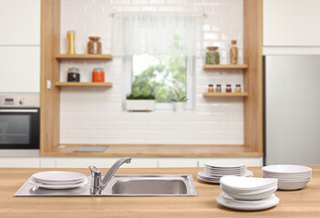 Piles of clean white plates next to a stainless steel sink