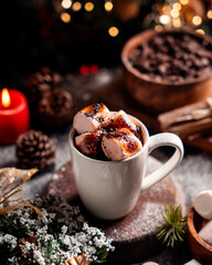 A cozy holiday scene with a cup of hot cocoa topped with charred, toasted marshmallows. 