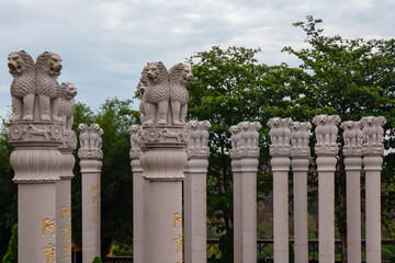 Fototapeta premium Row of tall, cylindrical columns with intricate carvings and lion stone sculpture on top. Chinese temple Patung Seribu (Vihara Ksitigarbha Bodhisattva, 500 Lohan Temple) on Bintan Island, Indonesia