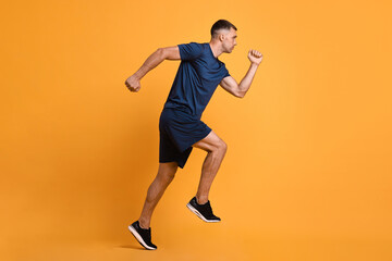 Fototapeta na wymiar Man in sportswear running on orange background