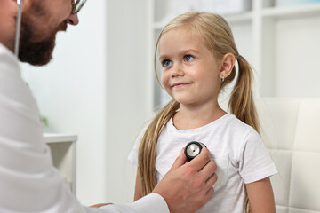 Fototapeta premium Doctor examining little girl with stethoscope in hospital, closeup