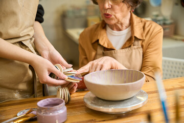 Women choosing colors for painting a clay bowl