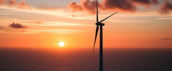 Obraz premium A towering wind turbine stands against a stunning coastal sunrise, its blades slowly rotating as the first light of day paints the sky in shades of orange, pink, and blue. 