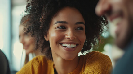 A close-up shot of an engaged workgroup in mid-discussion, their cheerful faces reflecting optimism and energy. The blurred background of the office allows the focus to remain on their collaborative,