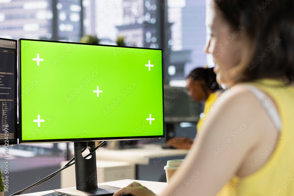 Poster worker conducting code review on green screen computer to fix bugs, identifying performance and tech