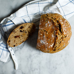 Whole wheat sourdough bread baked with olives and sundried tomatoes sitting on blue and white...