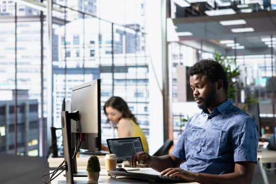 System administrator conducting detailed code review to fix bugs, identifying potential performance and technical issues with company software. African american man debugging and optimizing code