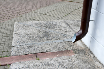 neat drainage for water from the building to the sidewalk in a special ditch, different tiles, joints on tiles, metal pipe for waste water