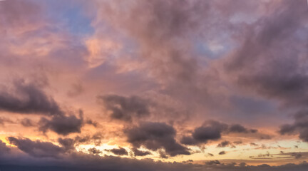 A beautiful sky tinted by the sun leaving vibrant shades of gold, pink, blue and multicolored. Clouds in the twilight evening and morning sky. Cloudy sky background in the evening, and during the day.