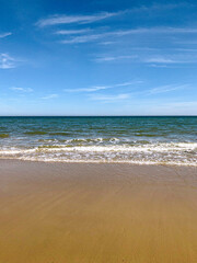  golden sand beach with turquoise sea and white waves on a summer day with blue sky
