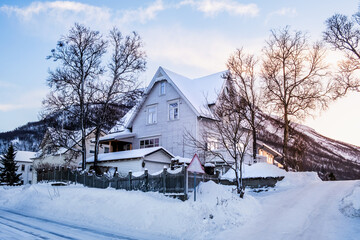 White wooden house in winter landscape of nordic town Tromso, Norway. Scandinavian generic architecture on Tromsoya island in Arctic circle. Winter wonderland with a lot of snow