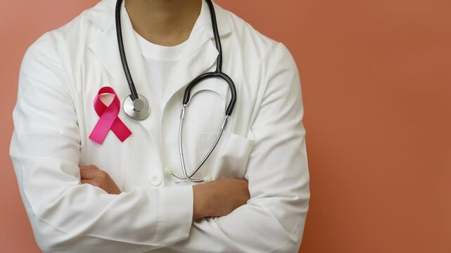 A doctor wearing a pink ribbon, showing solidarity with the fight against breast cancer, pink background